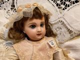 a doll that is sitting on a bed with a lace headband