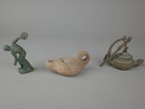 three small figurines of different shapes and sizes on a white surface