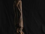 une sculpture en bois représentant un homme debout sur un morceau de bois