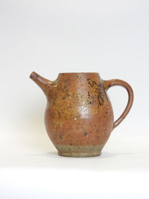 a small brown pitcher sitting on a white surface