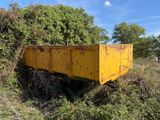 a yellow dumpster sitting in the middle of a field
