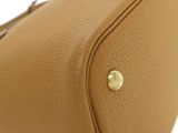 the back of a tan leather purse with a gold metal clasp
