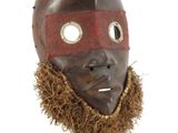 un masque en bois muni d'une barbe, posé sur un socle