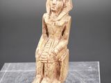 une statue égyptienne antique représentant une femme assise sur un rocher
