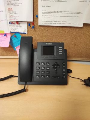 un téléphone posé sur un bureau devant un tableau d'affichage