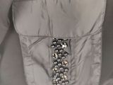 the back of a gray jacket with a black and silver beaded belt