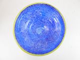 a blue bowl with a yellow rim sitting on a white surface