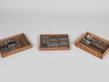 trois plateaux en bois contenant des fourchettes et des cuillères, posés sur une surface blanche