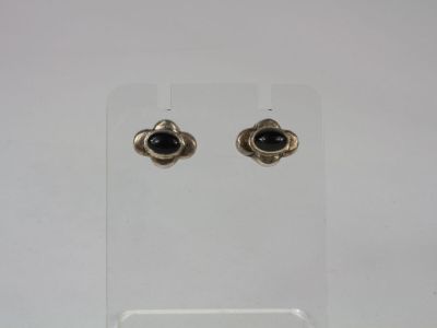 a pair of black stone earrings on a clear stand
