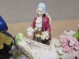 three figurines of a man and a woman riding on a horse