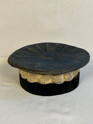 un chapeau noir et doré posé sur une table blanche
