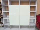 une bibliothèque blanche devant laquelle se trouve une chaise rouge