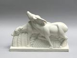 a white sculpture of a dog and a sheep on a table