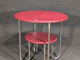 une table rouge sur laquelle se trouvent deux tabourets rouges