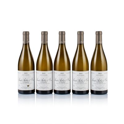 three bottles of white wine are lined up on a white surface