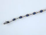 a close up of a bracelet with blue stones on a white surface