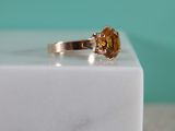 une image représentant une bague en or sertie d'une citrine, posée sur un bloc de marbre