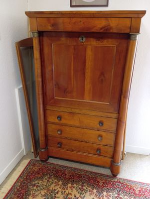 une armoire en bois dont la porte est ouverte, dans une pièce
