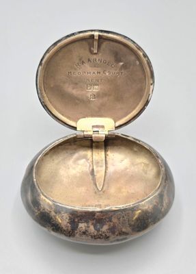 une vieille boîte en argent contenant un couteau, posée sur une surface blanche