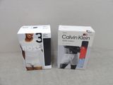 deux boîtes de sous-vêtements pour homme Calvin Klein posées sur un lit