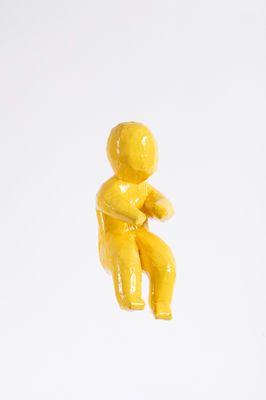 a small yellow figurine sitting on a white surface