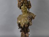 a bronze busturine of a woman with flowers on her head