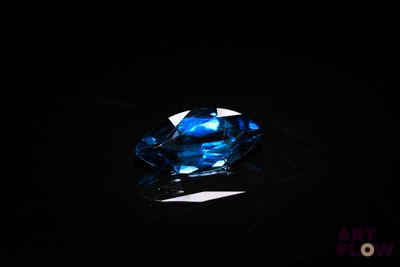 a close up of a blue diamond on a black surface