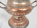 a silver vase with two handles on a white table
