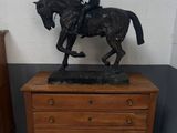 a statue of a man riding a horse on top of a dresser