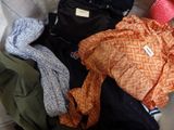 a pile of clothes sitting on the floor next to a suitcase
