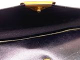 purple leather purse with gold hardware on top of it