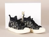 une paire de baskets noires et blanches posée sur une boîte blanche