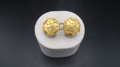 a close up of a pair of gold earrings on a white box