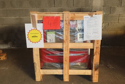 a wooden pallet with a red barrel and a sign on it
