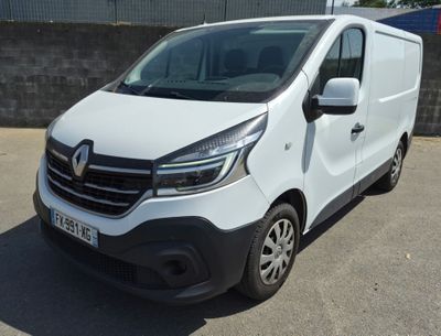 La camionnette blanche est garée sur le parking, à côté d'un mur de briques.