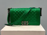 a green quilted purse sitting on top of a white box