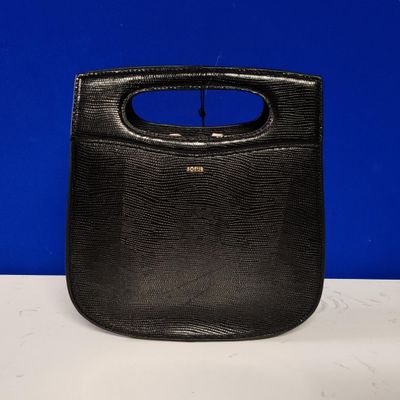 un sac à main noir muni d'une poignée, posé sur une table blanche
