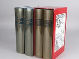 three books are sitting in a red box on a white surface