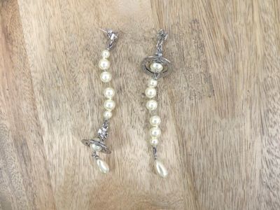 a pair of pearl and silver earrings on a wooden table