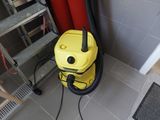 un aspirateur jaune posé par terre près d'un mur rouge