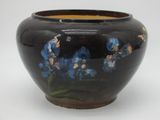 a black vase with blue flowers painted on it