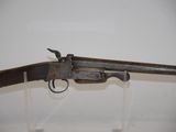 an old gun on display in a glass case on a white surface