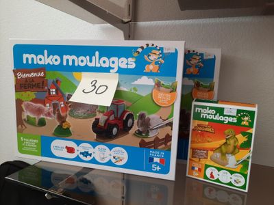 une boîte de moules à modeler et un tracteur jouet posés sur une table