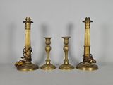 Trois bougeoirs en laiton ancien sont posés sur une table