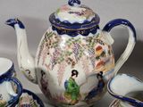 four pieces of porcelain teapots and cups sitting on a table