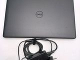 dell laptop with power cord and charger sitting on a white surface