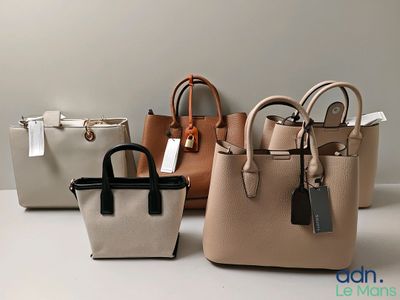Trois sacs à main sont alignés sur une table, avec des étiquettes accrochées dessus