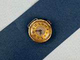 une montre en or posée sur une cravate bleue, sur une surface blanche