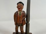 a wooden statue of a man standing next to a lamp post