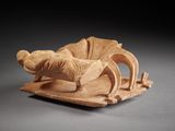 figurine of a reclining man on a sleigh